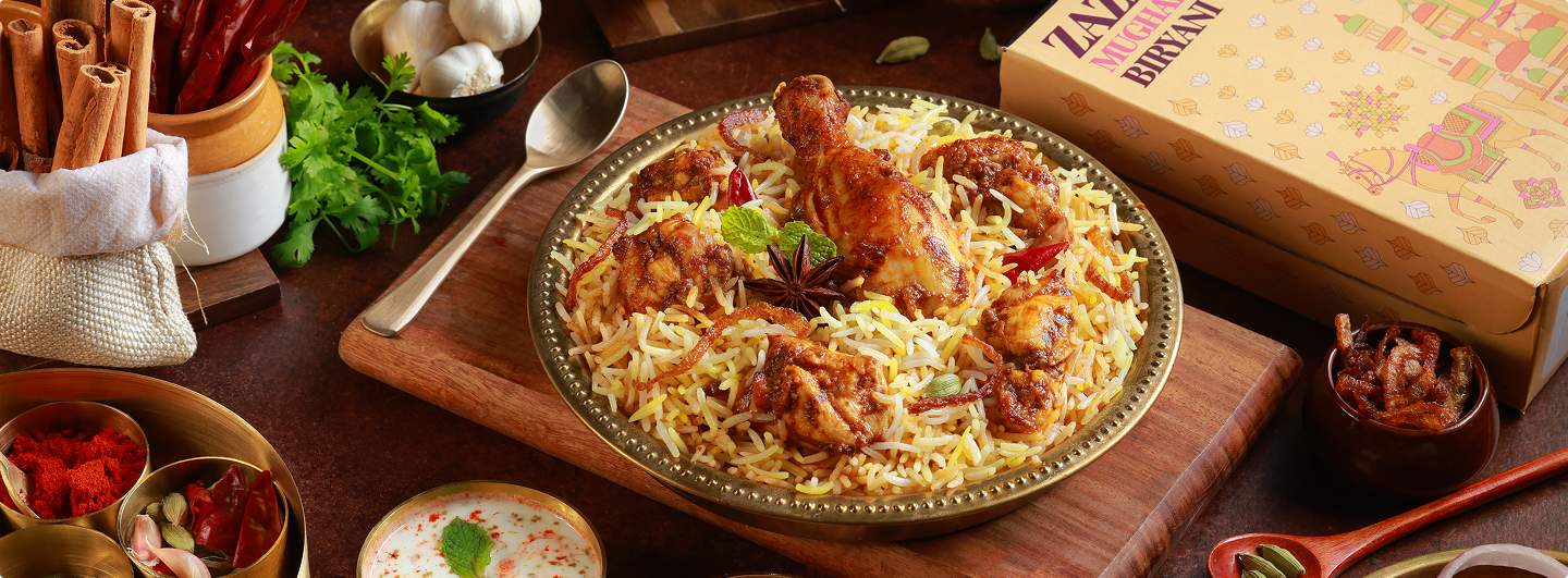 ZAZA Mughal Biryani beautifully plated with traditional spices, served in a brass plate alongside the signature packaging